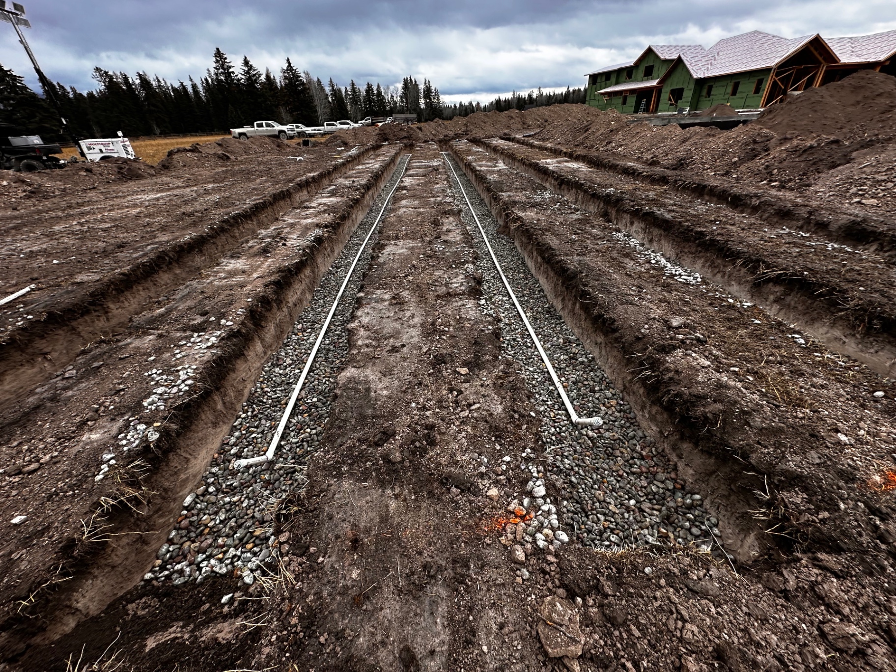Parallel footing trenches with drain rock and perforated pipe at new home site