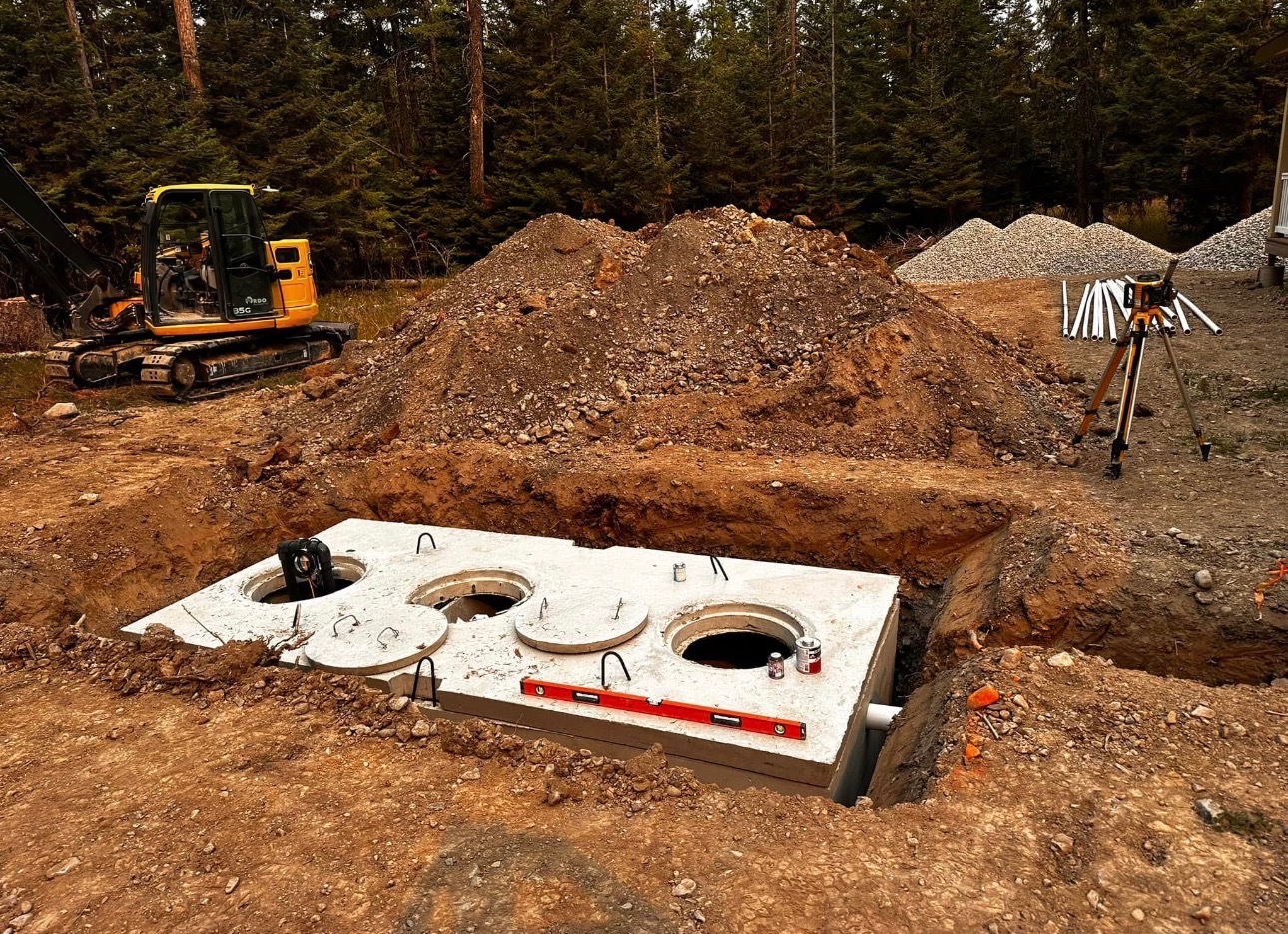 Concrete septic tank set in excavated pit with excavator and laser level on site
